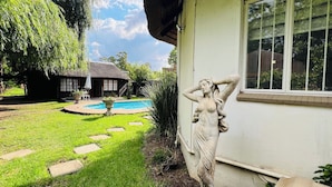 Een huis met een zwembad, een standbeeld en een tuin.