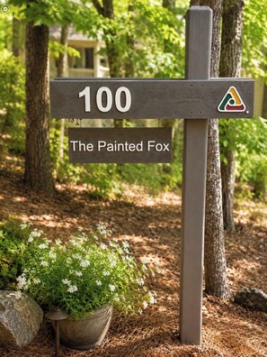 Un cartel de madera con el número '100' y el texto 'The Painted Fox' que indica un lugar.