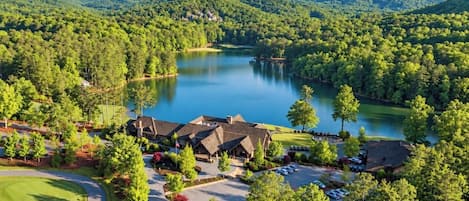 A lodge with a lake view, surrounded by forested hills.