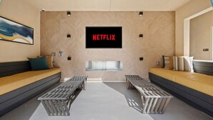 Ein modernes Wohnzimmer mit einem Netflix-Schild, zwei Sofas und einem Kamin.