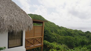 Una estructura de madera con techo de paja, con vistas a un paisaje verde exuberante y una masa de agua.