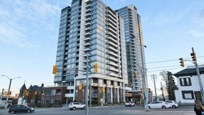 A high-rise building with multiple balconies, a modern architectural design, and a clear sky. - Contemporary Condo in DTK | Gym, Pool, & More (Kitchener)