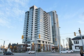 A high-rise building with multiple balconies, a modern architectural design, and a clear sky. - Contemporary Condo in DTK | Gym, Pool, & More (Kitchener)