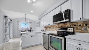 A modern kitchen with white cabinets, a microwave, an oven, and a dishwasher. - Spacious 3BR Upper Unit | Private Patio (Kitchener)