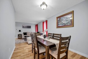 Un coin repas avec une table en bois, des chaises et un tableau accroché au mur.