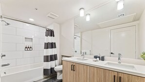 A modern bathroom with a shower, toilet, and vanity with a large mirror. - Bright & Modern Condo | 1Mi to South Coast Plaza (Santa Ana)