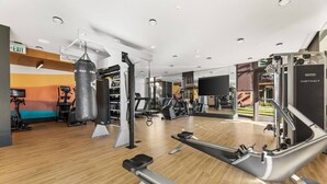 A modern gym with cardio machines, weightlifting equipment, and a punching bag. - Bright & Modern Condo | 1Mi to South Coast Plaza (Santa Ana)