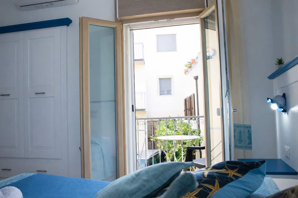 Une chambre à coucher comprenant un lit, une armoire, un balcon avec une table et des chaises, et une fenêtre.