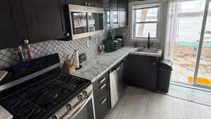 Una cucina moderna con mobili scuri, un piano cottura in acciaio inossidabile e una lavastoviglie.