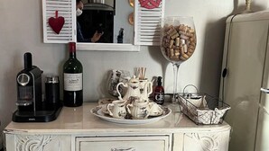 Ein antiker Schminktisch mit Spiegel, einer Weinflasche, einem Weinglas und einer Kaffeetassen-Servierplatte.