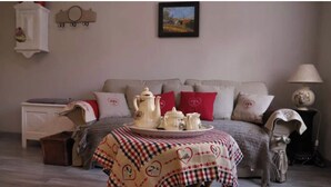 Ein gemütliches Wohnzimmer mit einer Couch, einem Tisch mit kariertem Tischläufer und einer Lampe.