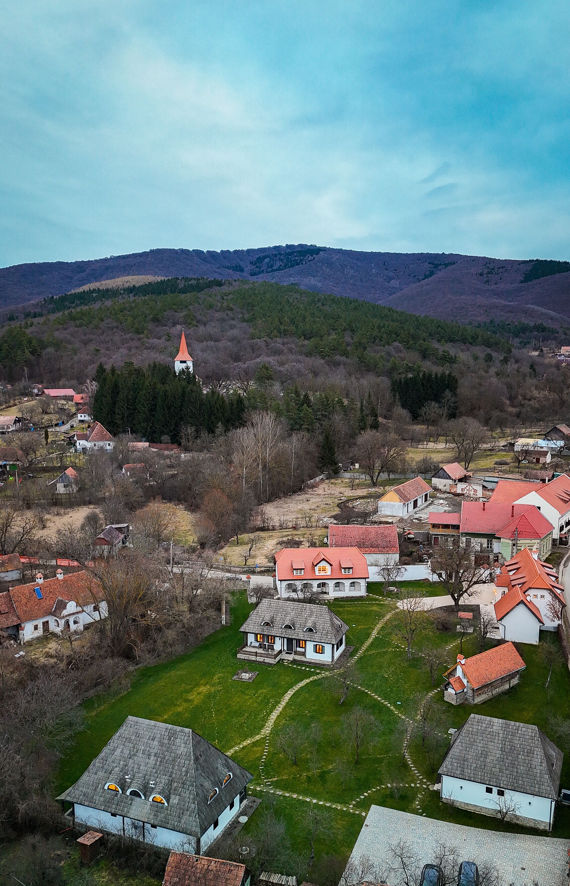 A village with a prominent church tower, surrounded by residential buildings with red roofs.