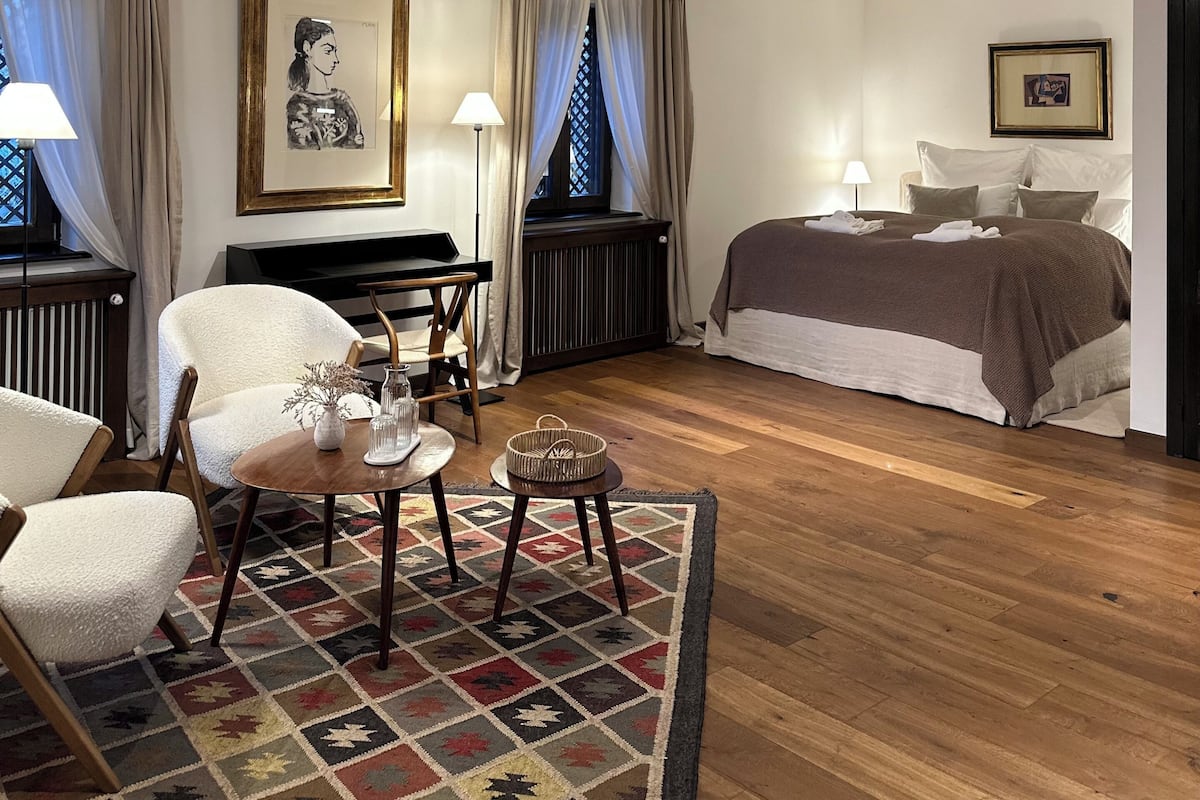 Una camera d'albergo con un letto, una scrivania, una sedia, una lampada e un quadro appeso al muro.