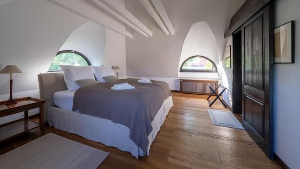 Une chambre à coucher avec un lit, une table de chevet, une fenêtre et un radiateur.