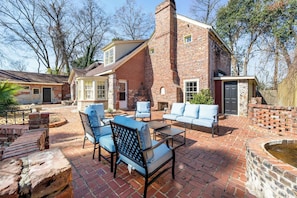 A brick house with a patio area featuring outdoor furniture and a fire pit. - Historic Brick Retreat w/ Sauna, Pool & Games (Columbus)