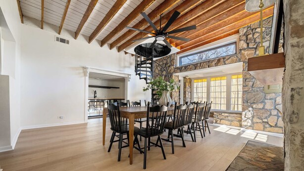 A dining area with a wooden ceiling, a stone wall, and a view of the outdoors. - Historic Brick Retreat w/ Pool & Games (Columbus)