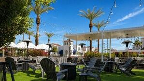 An outdoor seating area with chairs and tables, palm trees, and string lights. - Chandler Vacation Rental, 2 Bedroom Condo at The Cays with a Resort Pool & Spa (Chandler)