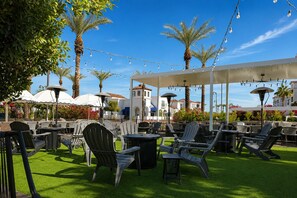An outdoor seating area with chairs and tables, palm trees, and string lights. - Chandler Vacation Rental, 2 Bedroom Condo at The Cays with a Resort Pool & Spa (Chandler)