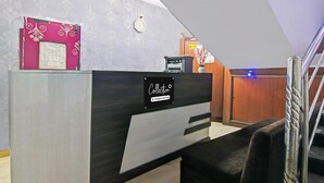 A reception desk with a 'Collection' sign, a clock, and a wooden panel on the wall. - Single Room Swagatam International Airport (Barakpur)