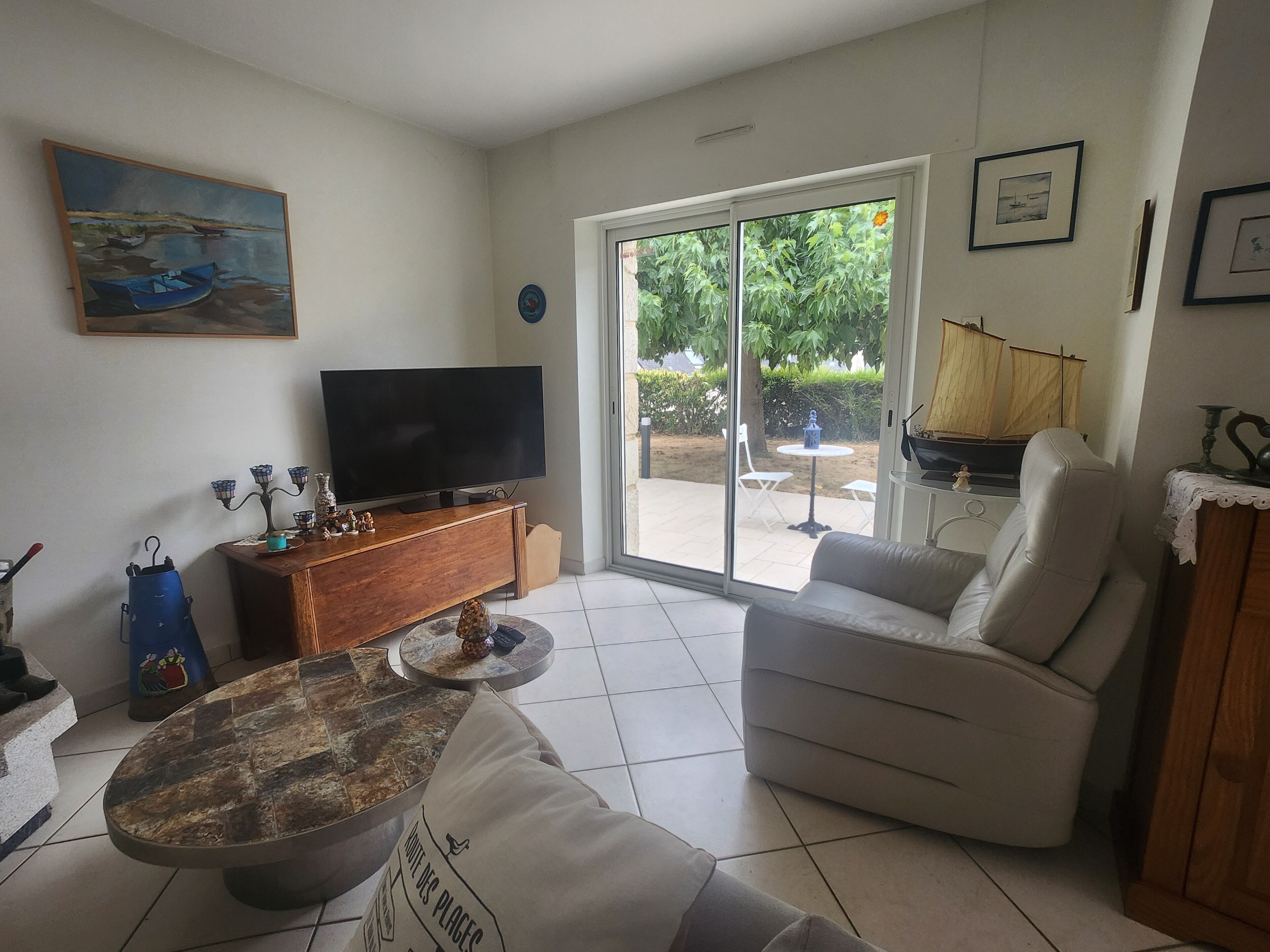 Ein Wohnzimmer mit Flachbildfernseher, einer Couch, einem Couchtisch und einem Essbereich mit Tisch und Stühlen.