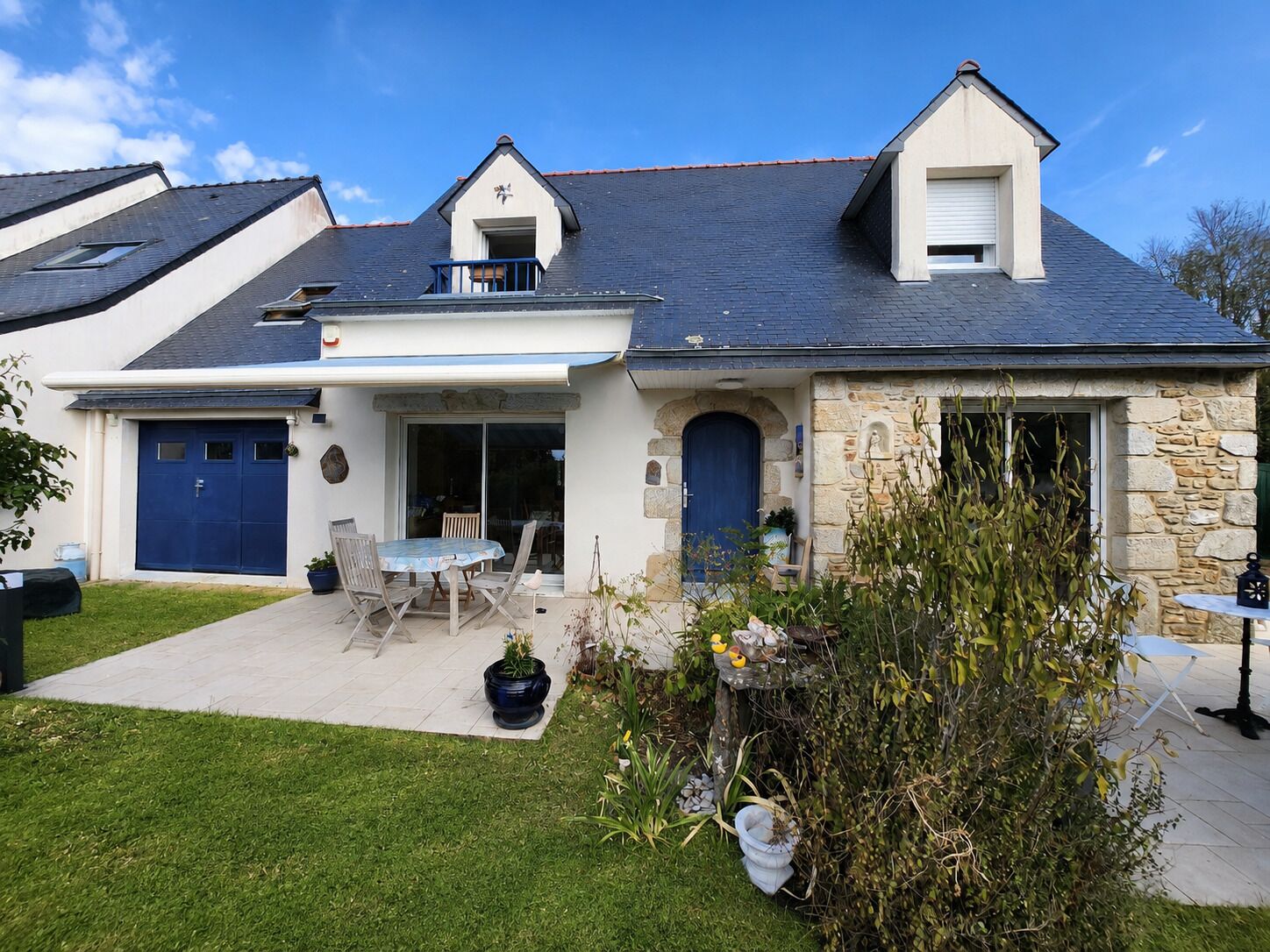 A two-story house with a covered patio, a stone facade, and a garage.