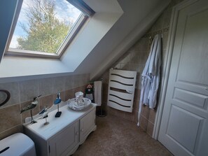 A bathroom with a skylight, a towel rack, and a sink with decorative items. - House 300 m from the ocean. Ocean view from the upper floor (Sarzeau)