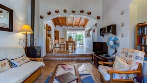 A cozy living room with a sofa, a coffee table, a TV, a fan, and a fireplace. - Peaceful Algarve Couple Escape With Pool (Portimão)
