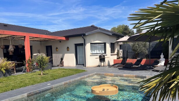 A swimming pool with clear water, a lounge area with chairs, and a building with a red roof. - Villa 5 bedrooms, Bali style with pool and jacuzzi, land 1700 m², near lake (Ambronay)