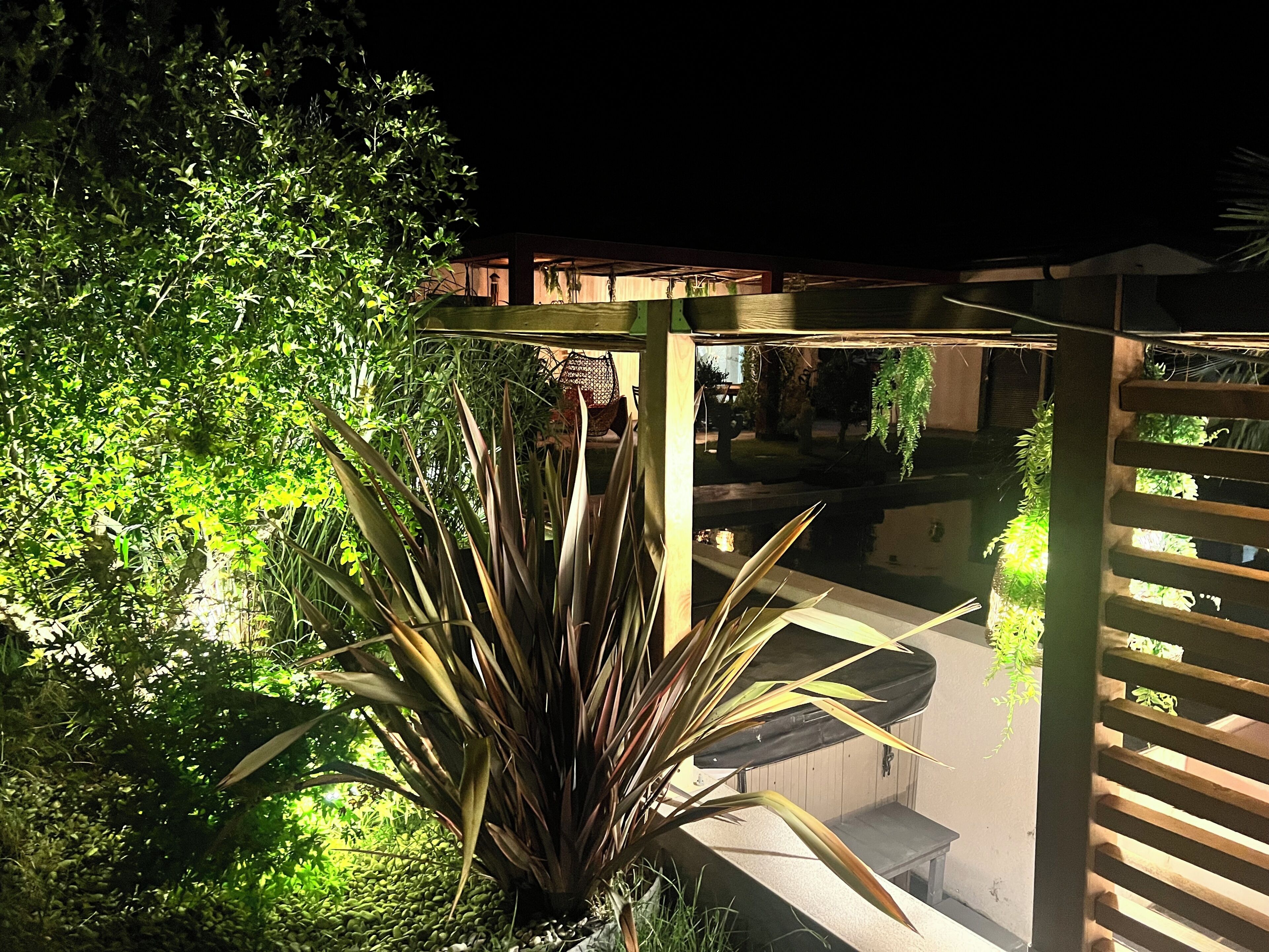 Ein überdachter Außenbereich mit Pool, umgeben von dichtem Grün und einer Holzpergola.