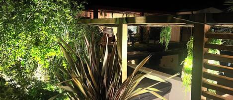 Ein überdachter Außenbereich mit Pool, umgeben von dichtem Grün und einer Holzpergola.