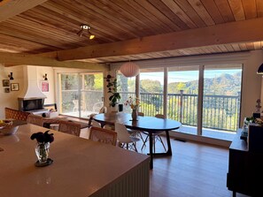 A spacious dining area with a large table, chairs, a fireplace, and a balcony with a view of the hills. - Spacious Hillside Mid-century Designer Home with Views (Glendale)