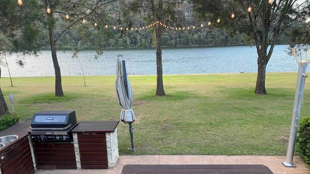 Une terrasse extérieure équipée d’un barbecue, d’une table de pique-nique et de guirlandes lumineuses.