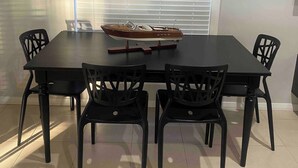 Un coin repas comprenant une table rectangulaire, quatre chaises et une fenêtre avec des stores.