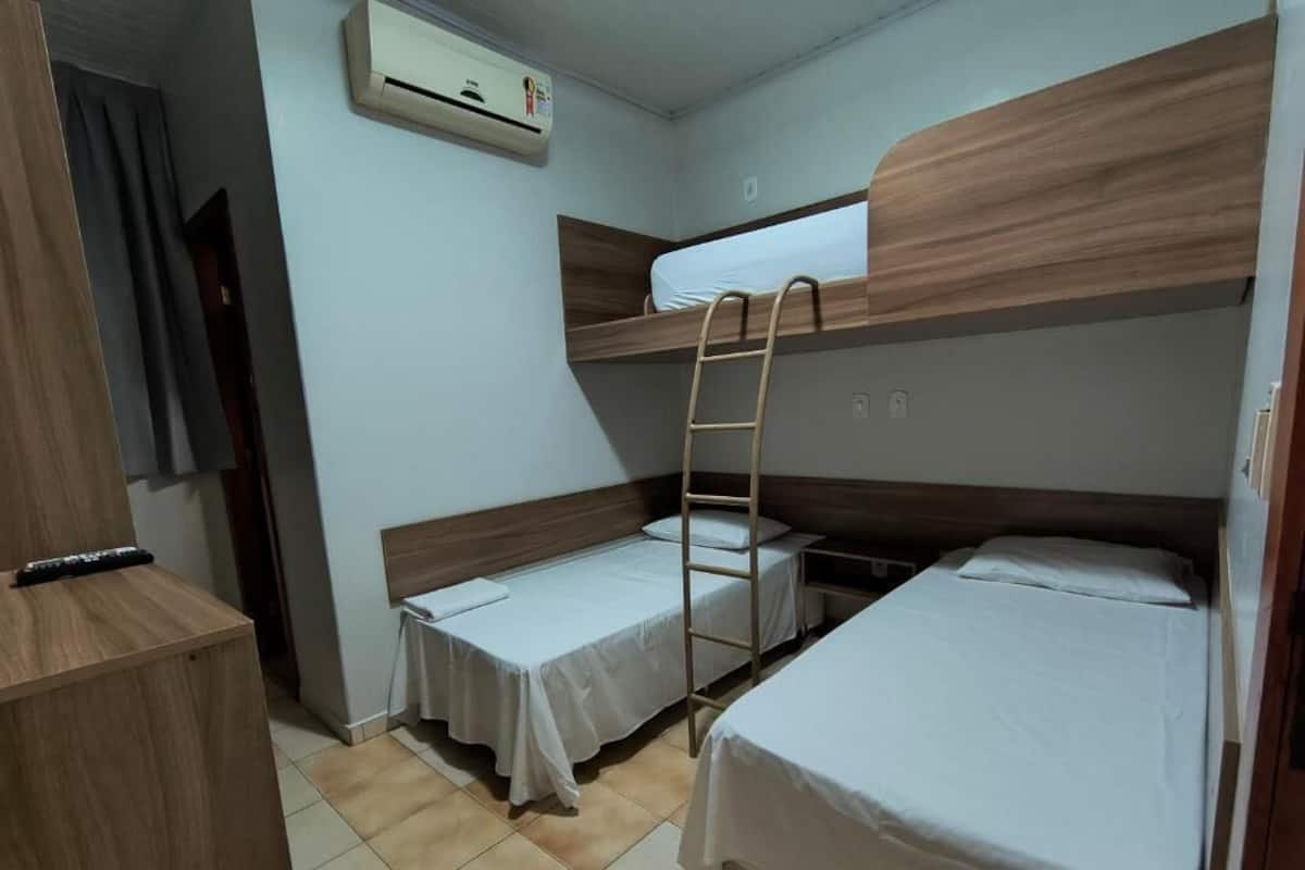 Una habitación con literas, una escalera, un escritorio y un equipo de aire acondicionado.