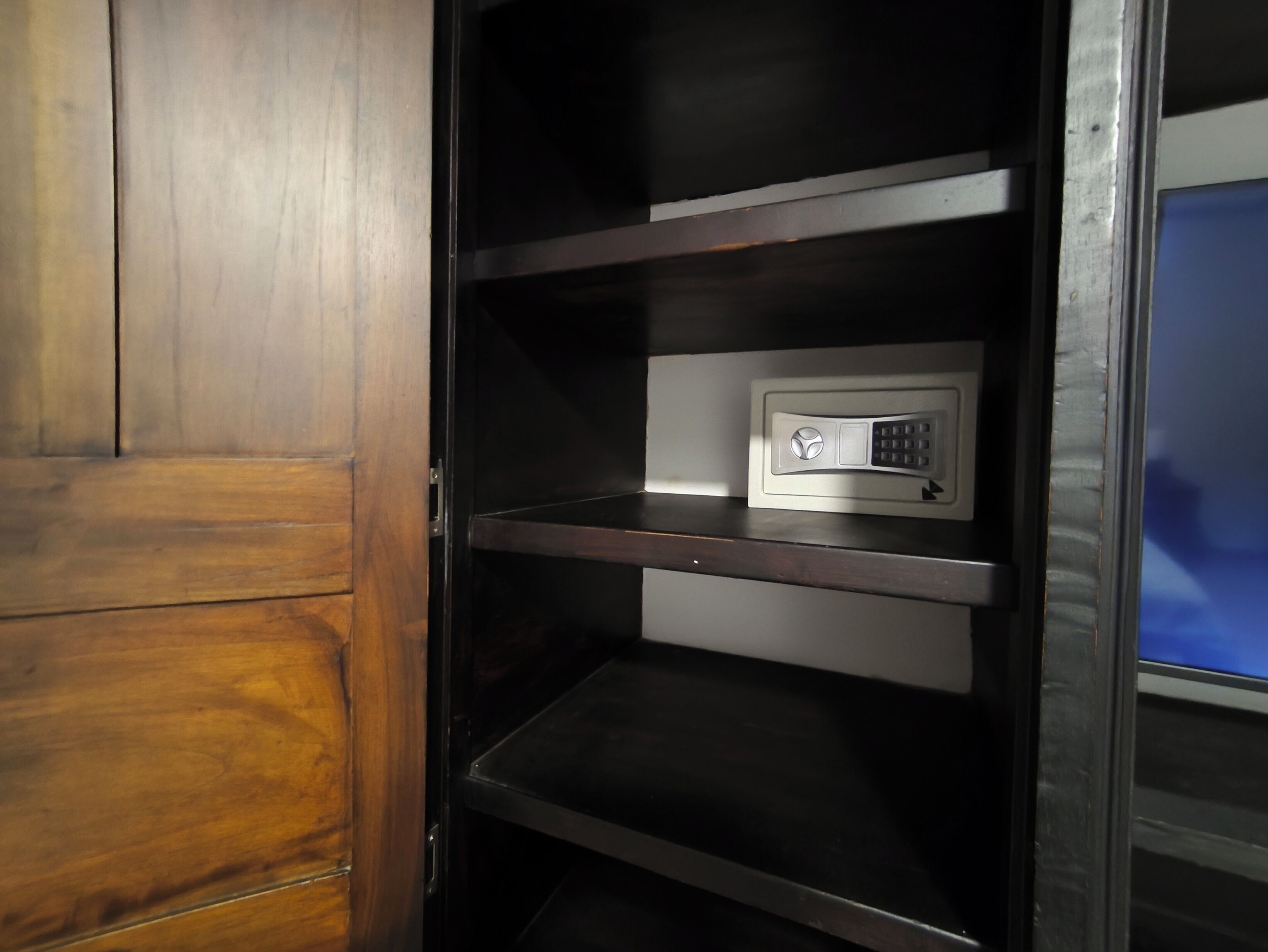 A room with a wooden door, a metal shelf, and a security keypad.