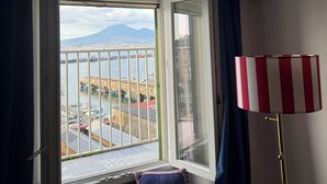 Une pièce avec une fenêtre donnant sur un port, un radiateur et une lampe à rayures.