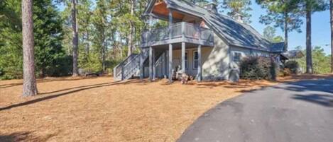 A two-story house with a porch, surrounded by trees.