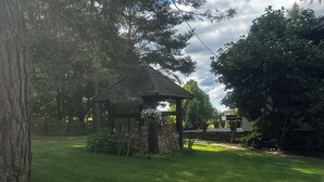 En lusthus i ett grönområde med träd och en stenmur.