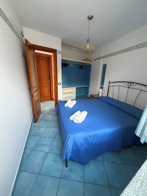 A bedroom with a bed, a wardrobe, a hanging light fixture, and a door. - Holiday home just 5 minutes from the sea. All the comforts, ideal for families. (Forio)