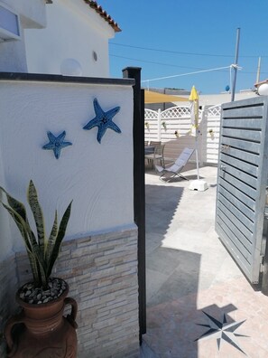 A patio area with a white wall, two starfish decorations, a potted plant, and a tiled floor. - Holiday home just 5 minutes from the sea. All the comforts, ideal for families. (Forio)