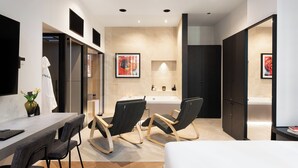 A modern hotel room with a bed, a desk, two rocking chairs, a bathroom with a bathtub, and artwork on the walls. - At Forty-One Apt 02 (Rome)