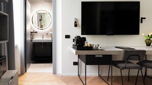 A modern hotel room with a flat-screen TV, a coffee station, a dining area with a table and chairs, and a bathroom with a mirror and sink. - At Forty-One Apt 02 (Rome)