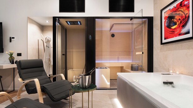 A modern bathroom with a large bathtub, a glass shower enclosure, and a seating area with chairs. - At Forty-One Apt 02 (Rome)