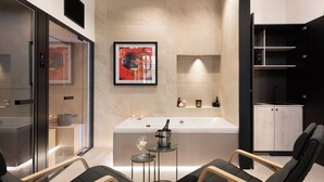 A modern bathroom with a bathtub, a glass-enclosed shower, and a small table with a bottle and glasses. - At Forty-One Apt 02 (Rome)