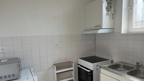 A compact kitchen with white cabinets, a built-in oven, a microwave, and a sink. - 5 minutes from the train station! Bright and spacious apartment (Romilly-sur-Seine)