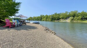 Un cadre idyllique au bord du lac, avec un belvédère, des fauteuils Adirondack, un bateau et une jetée.