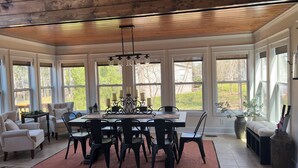A sunroom with a large table, chairs, and a chandelier. - Lake Front Home with Fireplace Private Boat Dock & Kayaks (Milledgeville)