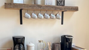 A kitchen counter with a coffee maker, a jar, and a wooden shelf above holding mugs. - Lake Front Home with Fireplace Private Boat Dock & Kayaks (Milledgeville)