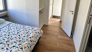 A bedroom with a bed, a wardrobe, and a door leading to another room. - Charming cottage (Le Mans)