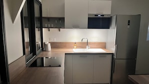 A modern kitchen with a built-in oven, a stainless steel refrigerator, and a wooden countertop. - Charming cottage (Le Mans)
